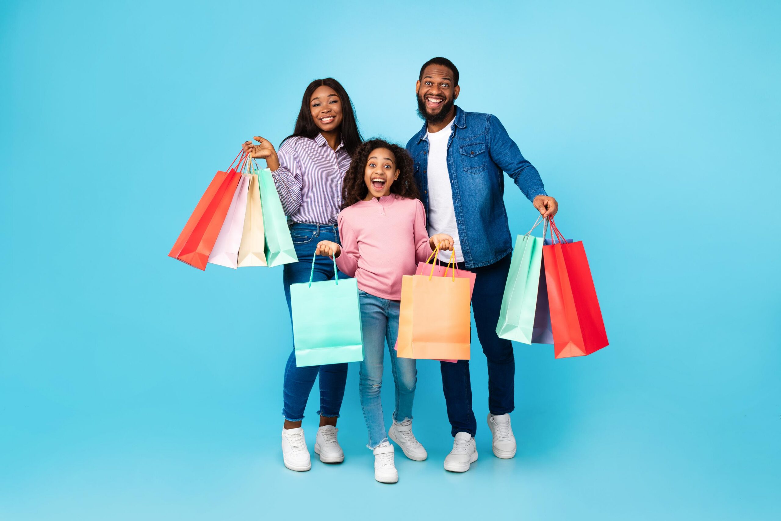 Family of three posing with shopping bags of brand-name finds