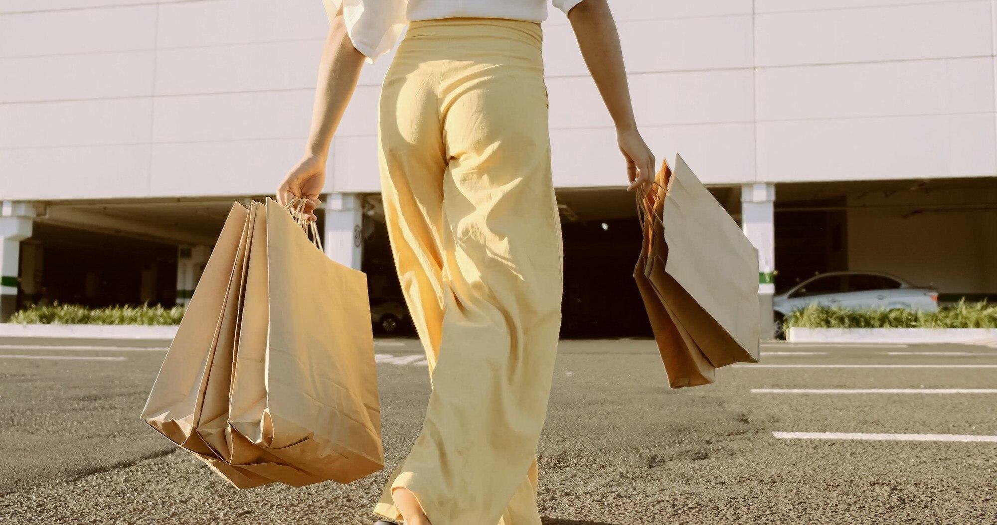Smiling shopper with bags of discounted brand-name clothing